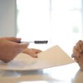 Crop businessman giving contract to woman to sign